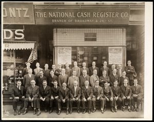 1916年にニューヨークのブロードウェイと28番街の支店の前でポーズをとったNational Cash Register Co.の男性のグループ（シルバーゼラチンプリント）